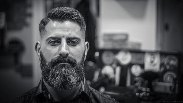 Minoxidil barba; imagen en blanco y negro y con un fondo desenfocado, mostrando el primer plano de un hombre serio con barba abundante al emplear el Minoxidil.